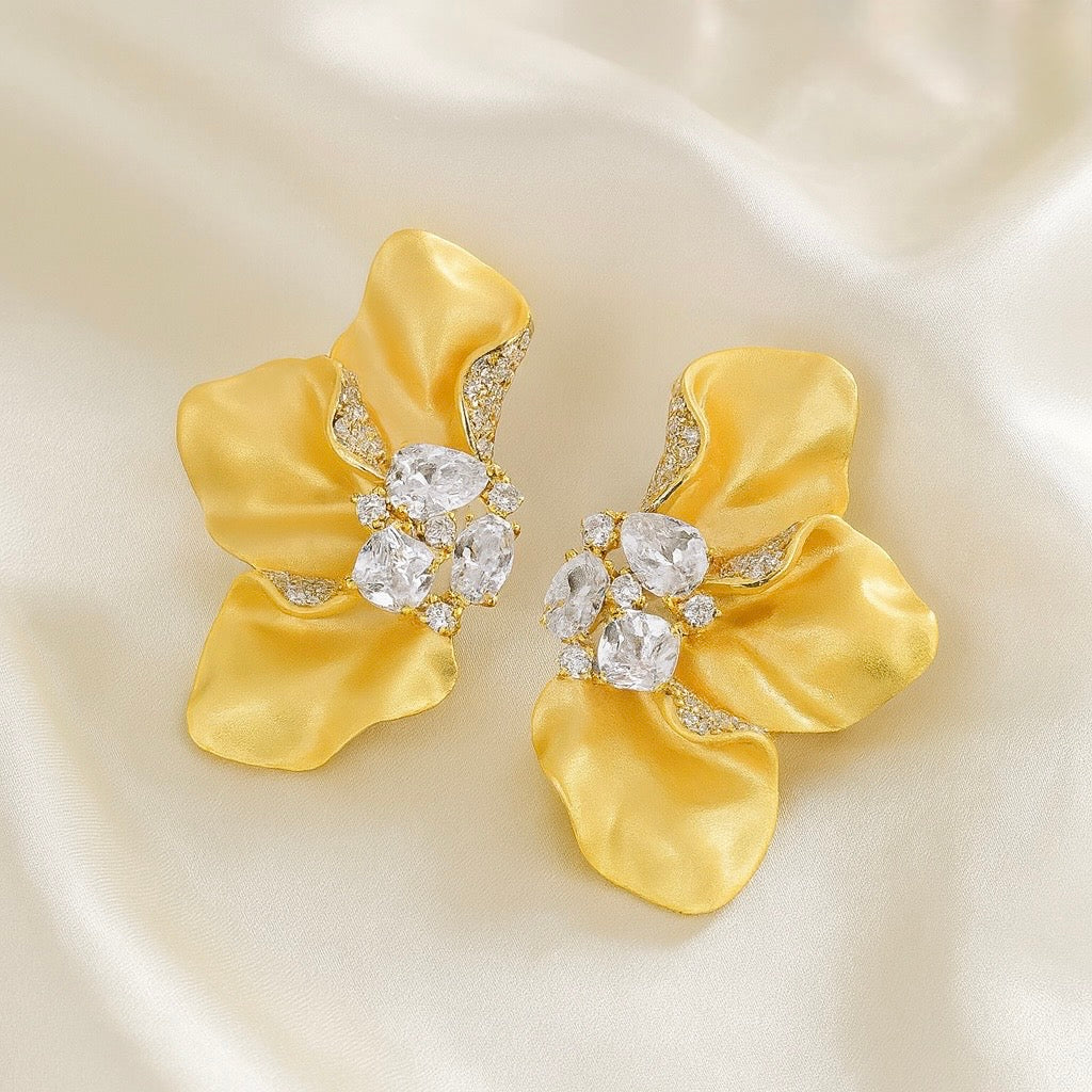 Sculptural Brushed Gold floral petal earrings with zirconia white gemstones on a silk background