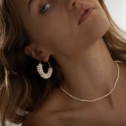 Woman wearing gold hoop earrings with dangling freshwater pearls for an elegant, feminine look