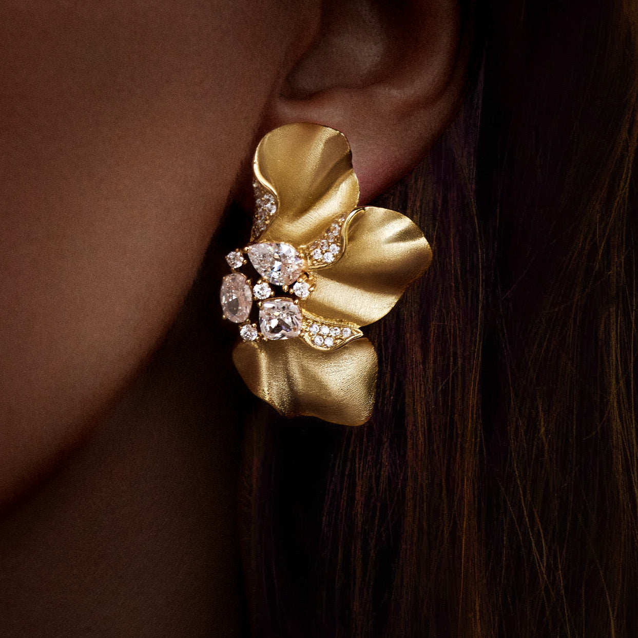 Sculptural Brushed Gold floral petal earrings with zirconia white gemstones on an evening