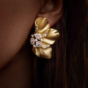 Sculptural Brushed Gold floral petal earrings with zirconia white gemstones on an evening