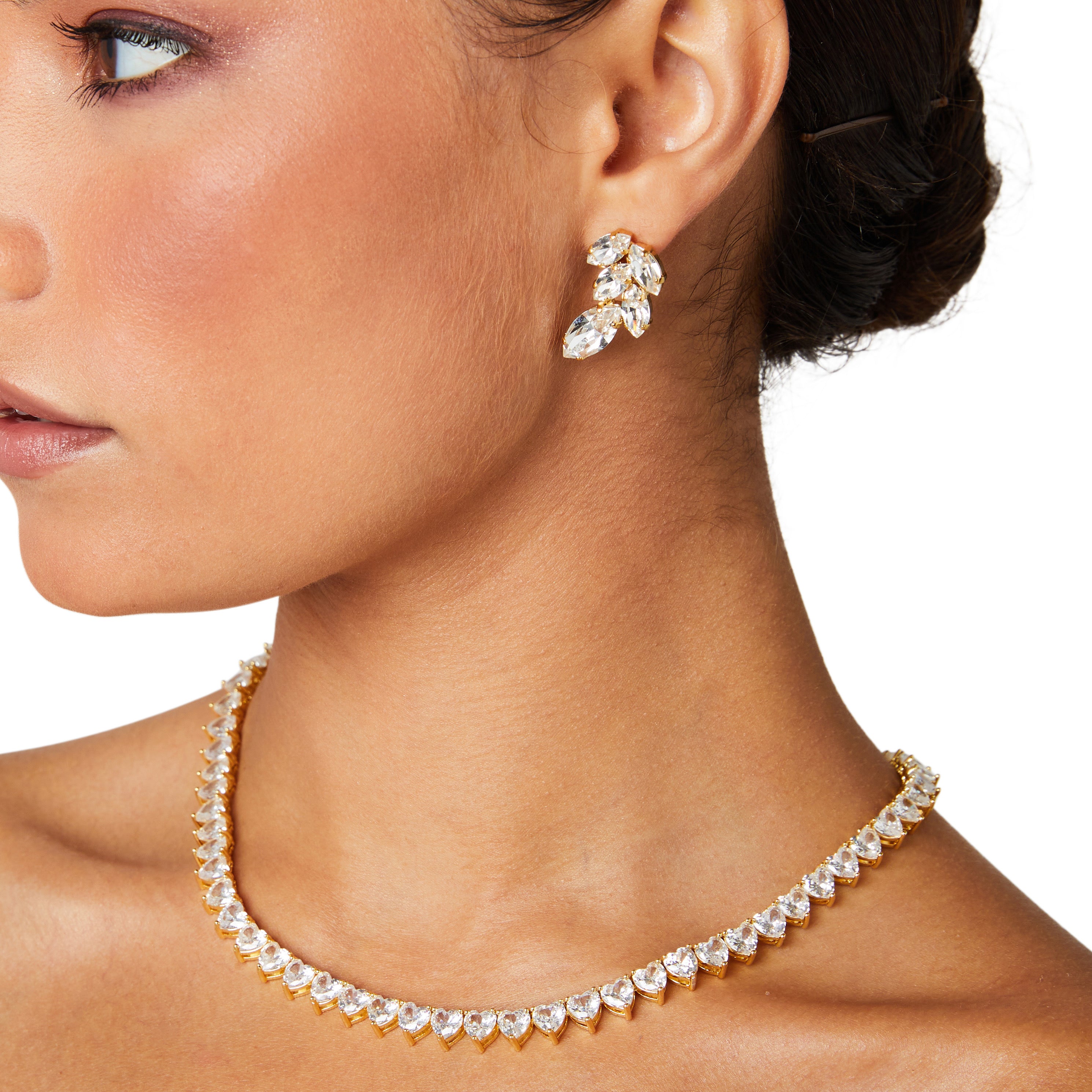 A deluxe tennis-style necklace composed of 7 mm heart-shaped clear cubic zirconia stones, each set in polished 18 ct gold plating. The hearts are aligned closely along a 16‑inch (40 cm) chain, creating a continuous sparkle around the neckline. The design features a secure, invisible clasp hidden behind one stone for a seamless look. The high-reflective gold finish and perfectly cut CZs give the piece a luxurious, radiant appeal—ideal for special occasions or elevating everyday style. It weighs approximately