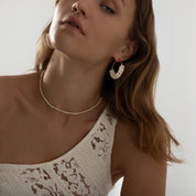 Woman wearing gold hoop earrings with dangling freshwater pearls for an elegant, feminine look