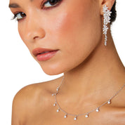 Silver long drop earrings with cascading floral embellishments, tapering to a delicate point; sparkling statement jewelry perfect for weddings, holidays, and special occasions.