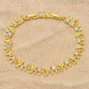 A delicate gold‑plated link bracelet featuring a whimsical parade of stylised elephant silhouettes, each linked trunk-to-tail. The small elephant charms are uniformly sized with softly rounded bodies and upturned trunks, creating a playful, continuous chain. The bracelet is secured with an integrated box‑style clasp and lays flat when worn, measuring around 18 cm in length. The polished gold finish gives a warm, refined sheen, enhancing its charming, artisan-crafted look.