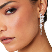 Silver long drop earrings with cascading floral embellishments, tapering to a delicate point; sparkling statement jewelry perfect for weddings, holidays, and special occasions.