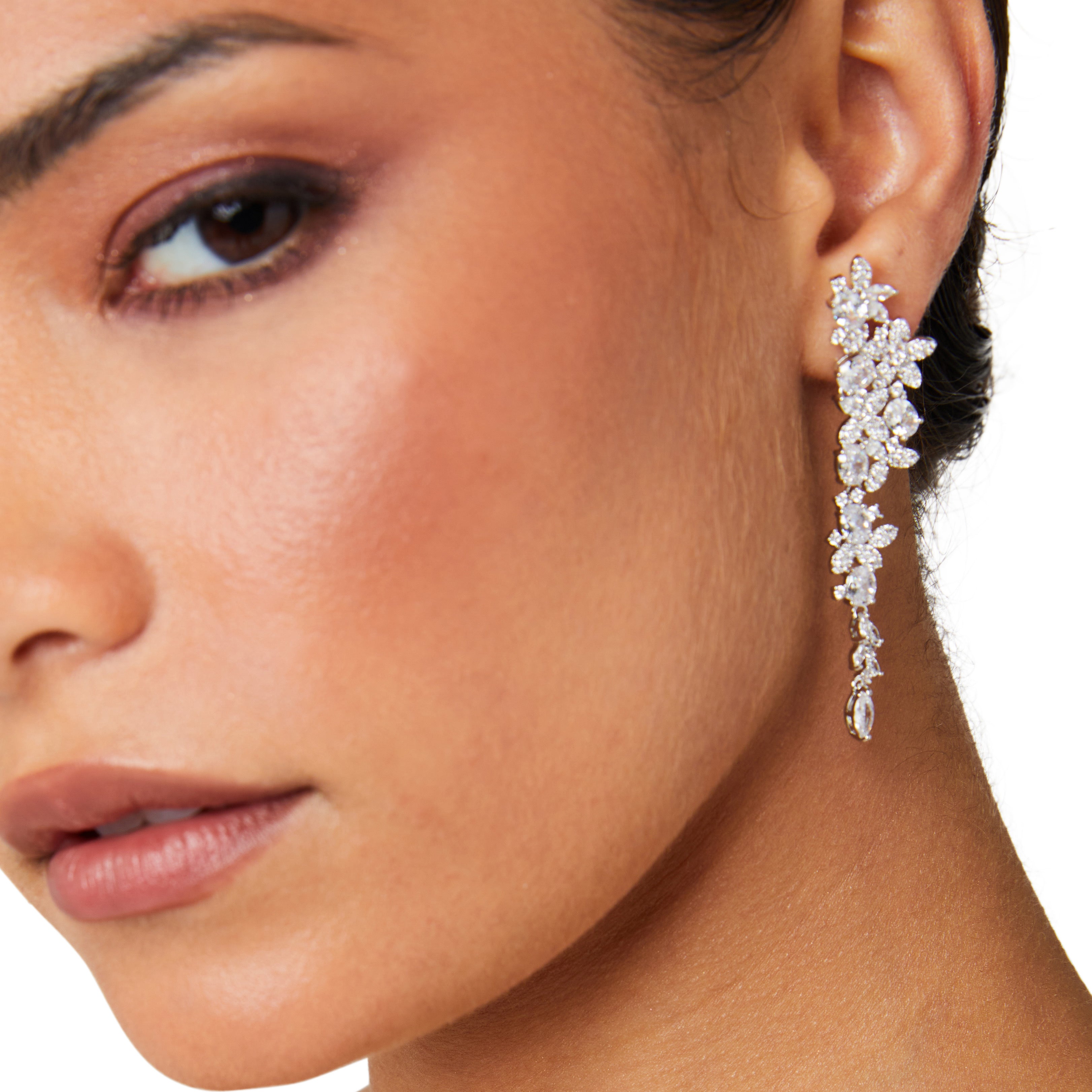 Silver long drop earrings with cascading floral embellishments, tapering to a delicate point; sparkling statement jewelry perfect for weddings, holidays, and special occasions.