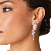 Silver long drop earrings with cascading floral embellishments, tapering to a delicate point; sparkling statement jewelry perfect for weddings, holidays, and special occasions.