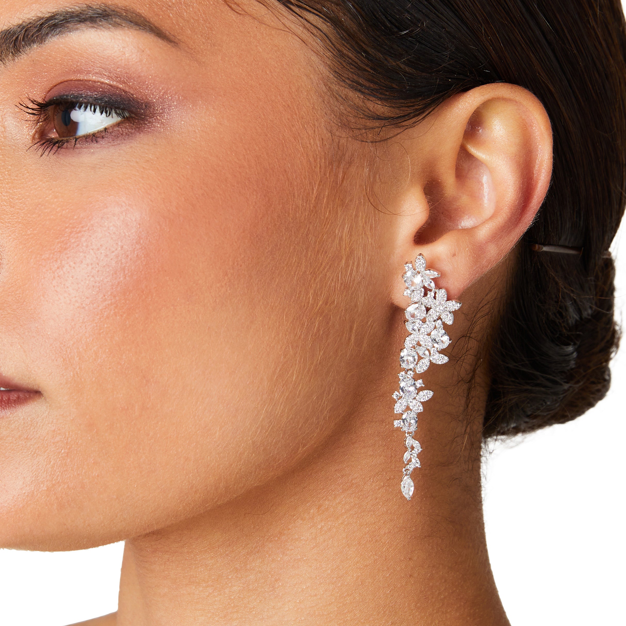 Silver long drop earrings with cascading floral embellishments, tapering to a delicate point; sparkling statement jewelry perfect for weddings, holidays, and special occasions.