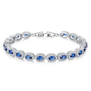 A silver tennis bracelet featuring oval cut blue crystals surrounded by white cubic zirconia.