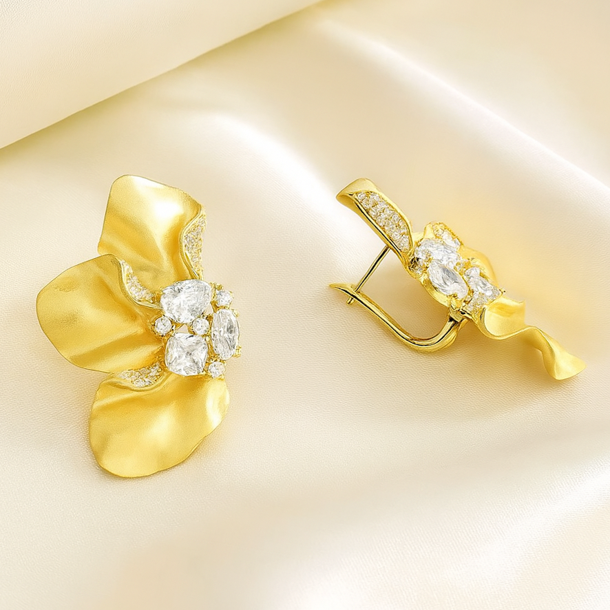Sculptural Brushed Gold floral petal earrings with zirconia white gemstones on a silk background