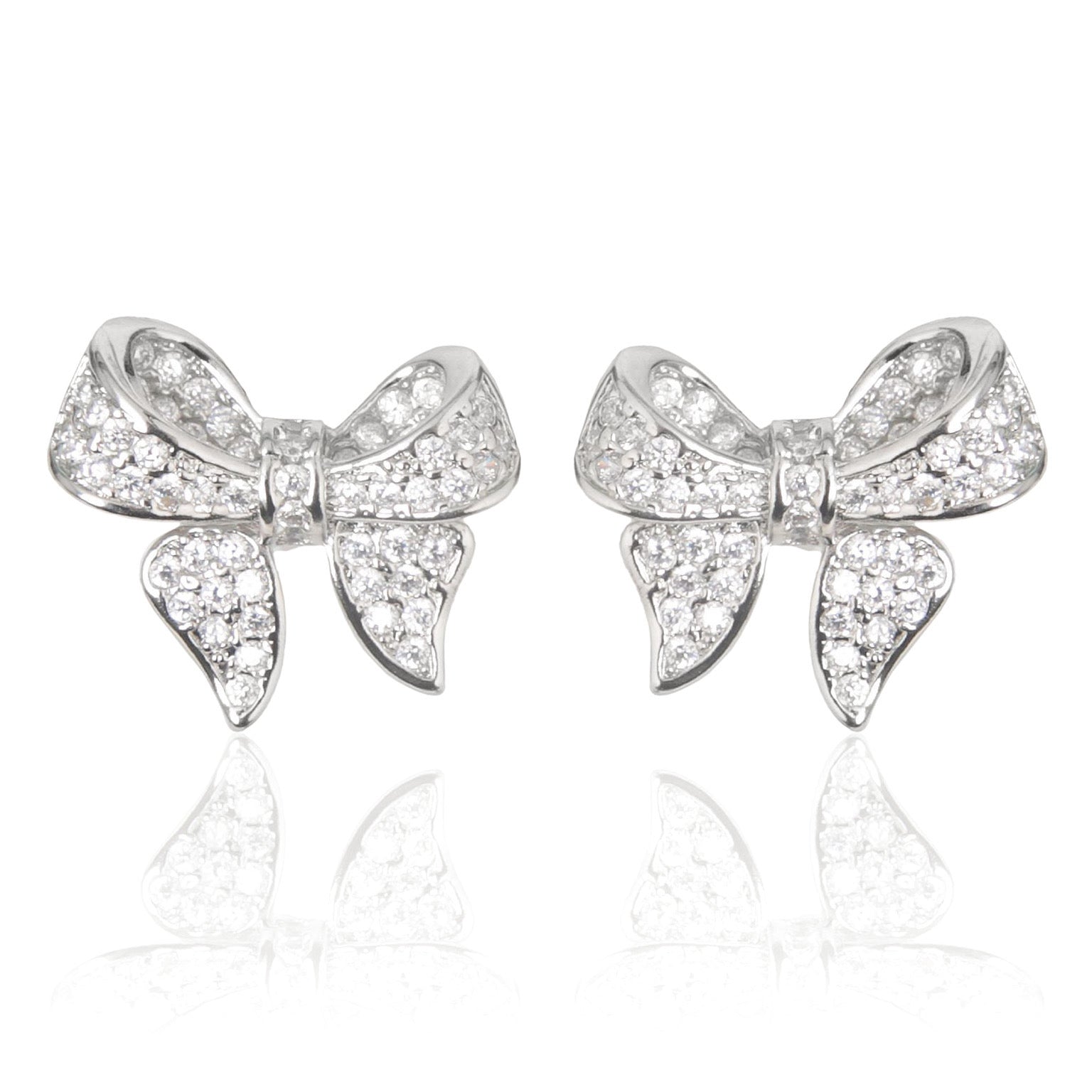 A pair of polished rhodium‑plated silver stud earrings shaped like stylised ribbon bows. Each bow features two gracefully looping ribbon forms with gently tapered tails that curve organically. The surface is smooth and reflective, catching light with soft gleams. The bows measure approximately 1.2 cm wide and 1 cm tall, and secure with standard butterfly push‑back posts. The design exudes charming femininity and understated elegance—a delicate accessory perfect for both everyday wear and subtle evening spa