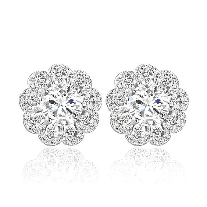 A pair of silver stud earrings with a floral lace edge design, featuring multiple small round cut gems.