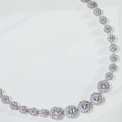 Silver crystal tennis necklace with graduated cubic zirconia stones haloed by pavé, rhodium-plated brass, displayed on a clean white background
