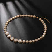 gold crystal tennis necklace with graduated cubic zirconia stones and pavé halos, photographed against a black background to highlight the necklace’s radiant sparkle and elegant design