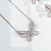 A delicately crafted rhodium-plated silver cable chain suspends a butterfly pendant measuring about 1.8 cm across. The butterfly’s wings are outlined and filled with sparkling white cubic zirconia crystals of varying cuts—round and baguette—creating a textured, shimmering mosaic. The pendant is centred on the chain, which measures 16 in (40 cm) and fastens with a small spring-ring clasp. The overall aesthetic is elegant, glimmering, and nature-inspired, perfect for adding a subtle yet eye-catching accent to