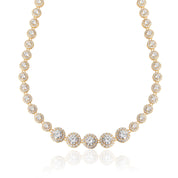 A gold-colored crystal tennis necklace with graduated sizes of clear cubic zirconia stones, presented against a white background.