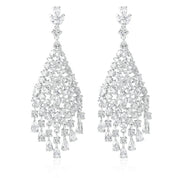 Silver chandelier earrings featuring cascading white cubic zirconia stones, rhodium-plated with a 6.4 cm drop, shown on model and against light and dark backgrounds.