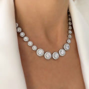 Model wearing a silver crystal tennis necklace featuring graduated cubic zirconia stones with halo pavé detailing, styled against a simple outfit to emphasize the necklace’s elegant sparkle