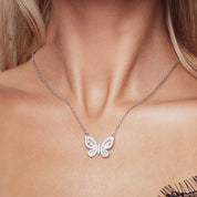 A delicately crafted rhodium-plated silver cable chain suspends a butterfly pendant measuring about 1.8 cm across. The butterfly’s wings are outlined and filled with sparkling white cubic zirconia crystals of varying cuts—round and baguette—creating a textured, shimmering mosaic. The pendant is centred on the chain, which measures 16 in (40 cm) and fastens with a small spring-ring clasp. The overall aesthetic is elegant, glimmering, and nature-inspired, perfect for adding a subtle yet eye-catching accent to