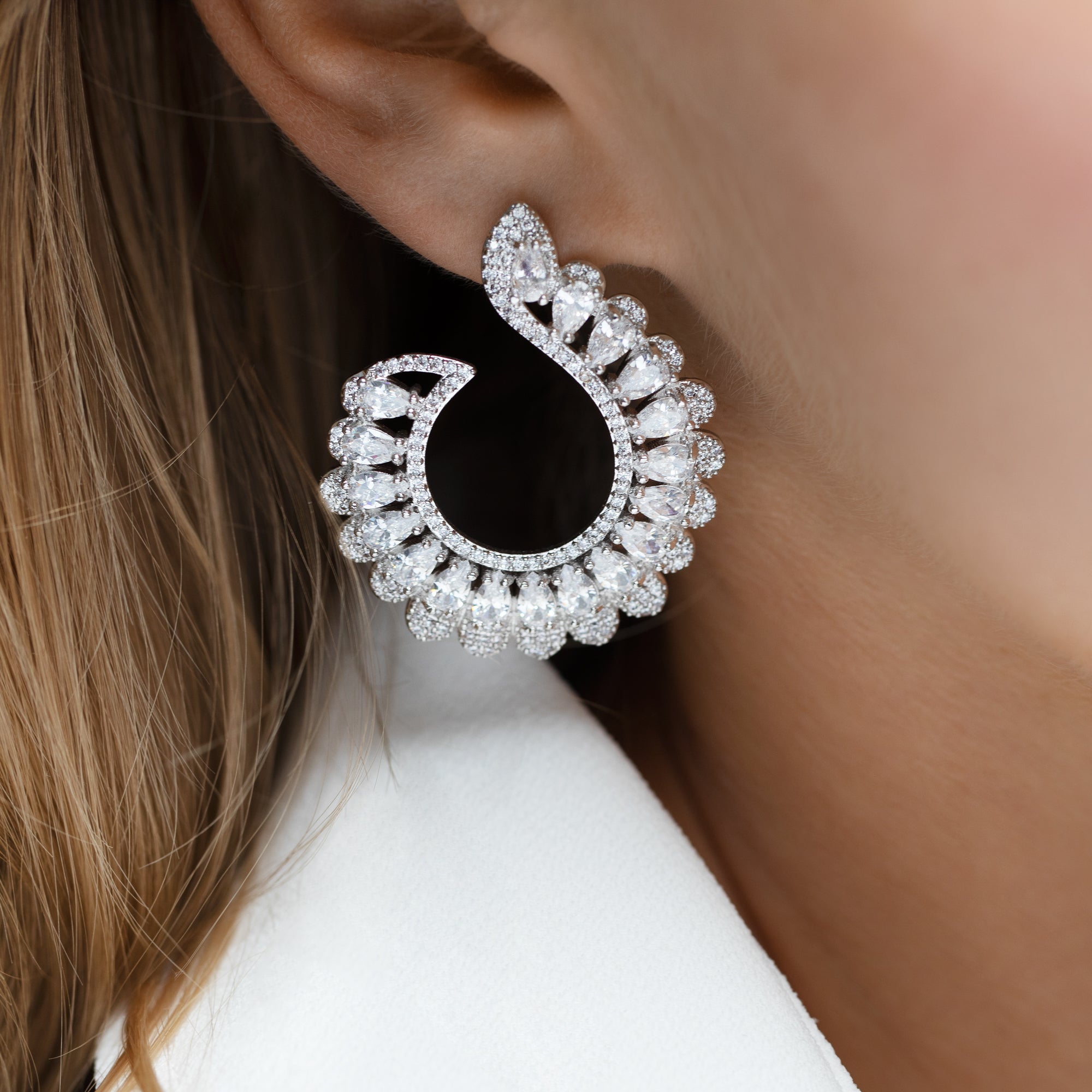 A pair of silver earrings featuring a geometric pattern with white cubic zirconia crystals, giving off a sparkling and elegant appearance.