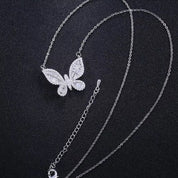 A delicately crafted rhodium-plated silver cable chain suspends a butterfly pendant measuring about 1.8 cm across. The butterfly’s wings are outlined and filled with sparkling white cubic zirconia crystals of varying cuts—round and baguette—creating a textured, shimmering mosaic. The pendant is centred on the chain, which measures 16 in (40 cm) and fastens with a small spring-ring clasp. The overall aesthetic is elegant, glimmering, and nature-inspired, perfect for adding a subtle yet eye-catching accent to