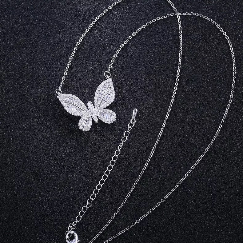 A delicately crafted rhodium-plated silver cable chain suspends a butterfly pendant measuring about 1.8 cm across. The butterfly’s wings are outlined and filled with sparkling white cubic zirconia crystals of varying cuts—round and baguette—creating a textured, shimmering mosaic. The pendant is centred on the chain, which measures 16 in (40 cm) and fastens with a small spring-ring clasp. The overall aesthetic is elegant, glimmering, and nature-inspired, perfect for adding a subtle yet eye-catching accent to