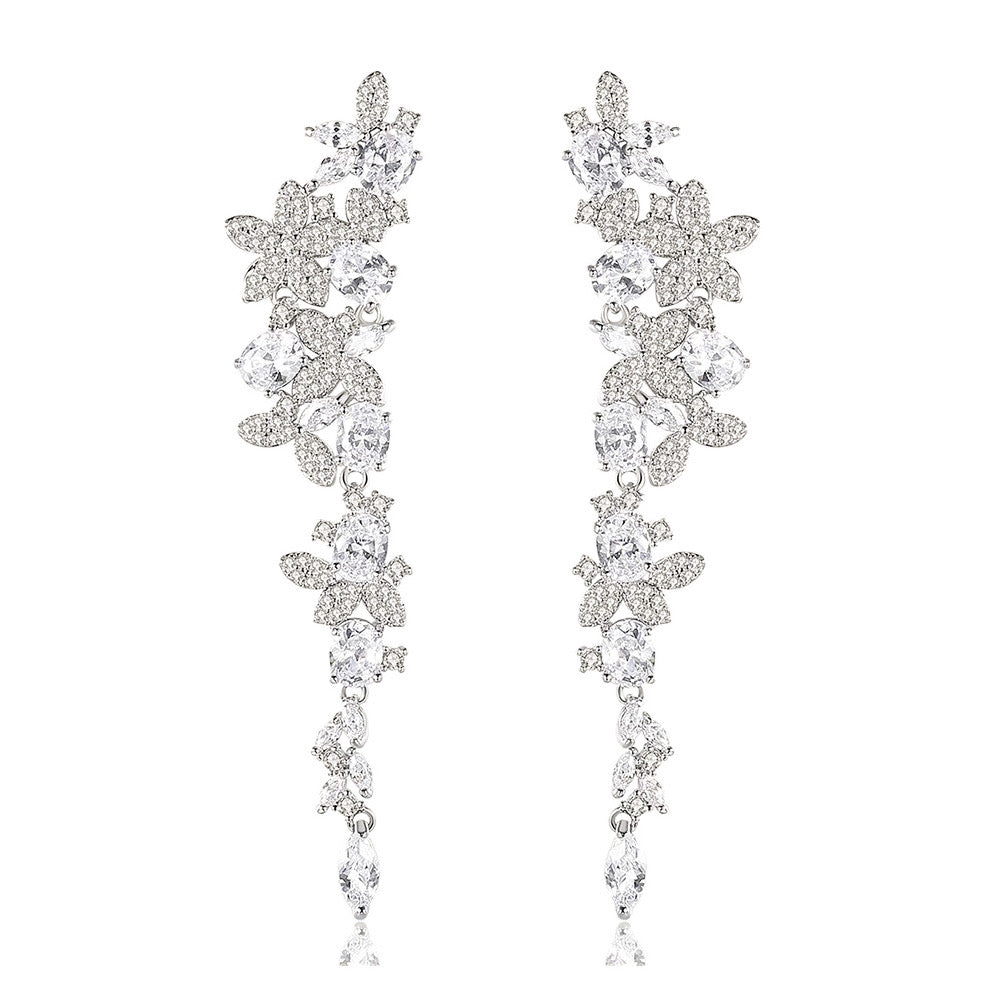 Silver long drop earrings with cascading floral embellishments, tapering to a delicate point; sparkling statement jewelry perfect for weddings, holidays, and special occasions.