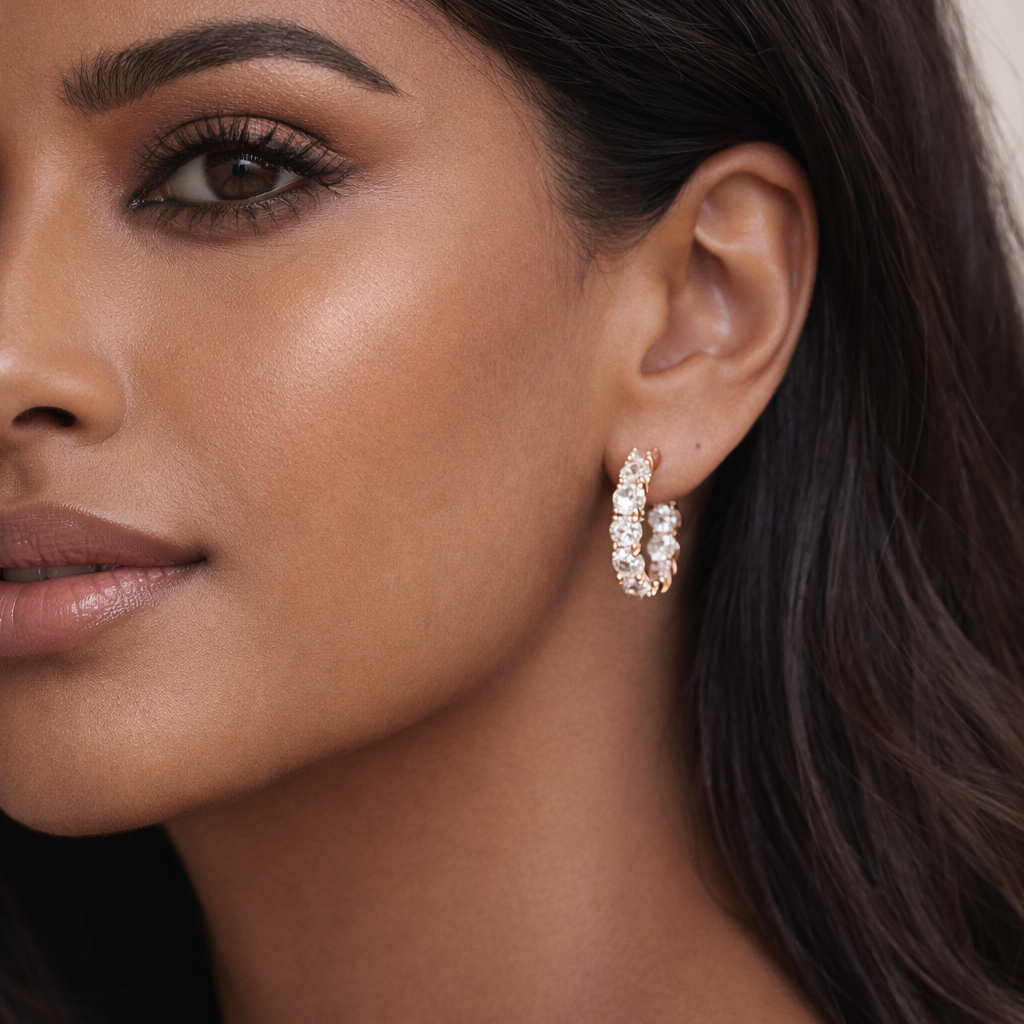 Close-up of a woman wearing diamond hoop earrings with a neutral background