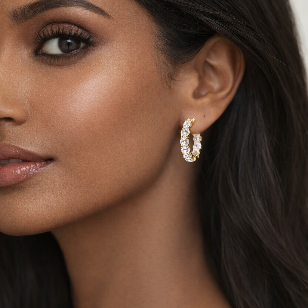 Close-up of a woman wearing gold hoop earrings with a neutral background