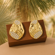 A pair of gold‑plated stud earrings, each shaped like three elegant, tapering wave arches that fan outward in a stylised, goddess-inspired design. The curved strands are smooth, mirror‑polished, and evenly spaced, creating a sense of movement and volume while remaining compact—approximately 1.3 cm tall from post to tip. They appear to sit snugly along the earlobe and fasten with standard push-back posts. The warm metallic sheen and sculptural silhouette evoke a graceful, contemporary luxury vibe.