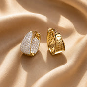 Gold hoop pave earrings with a beige fabric