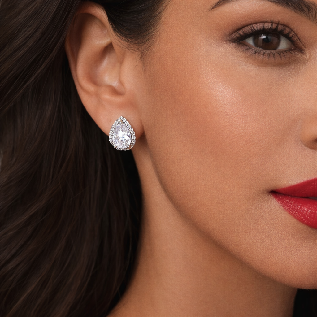 Close-up of a model wearing a silver pear cut earring with a blurred background