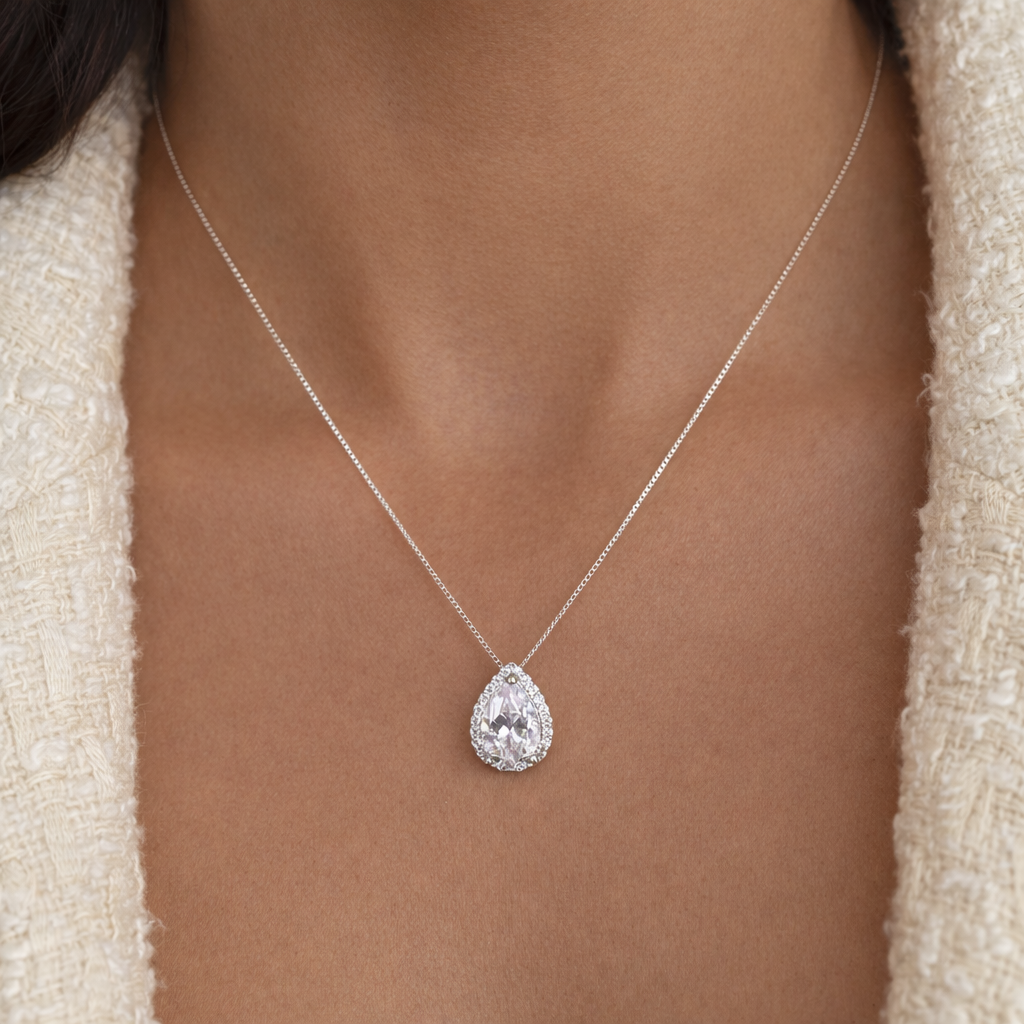 Teardrop-shaped diamond pendant on a necklace against a neutral background