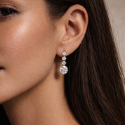 Close-up of a woman wearing crystal wedding earrings with a neutral background