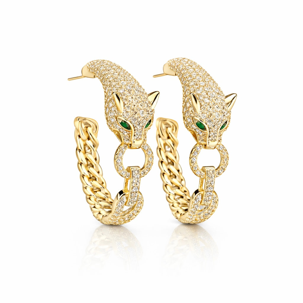 A pair of gold Valentina-rose hoop earrings featuring a panther head design paved with clear stones, with green emerald-cut eyes and a curb chain link design at the bottom, shown on a white background.