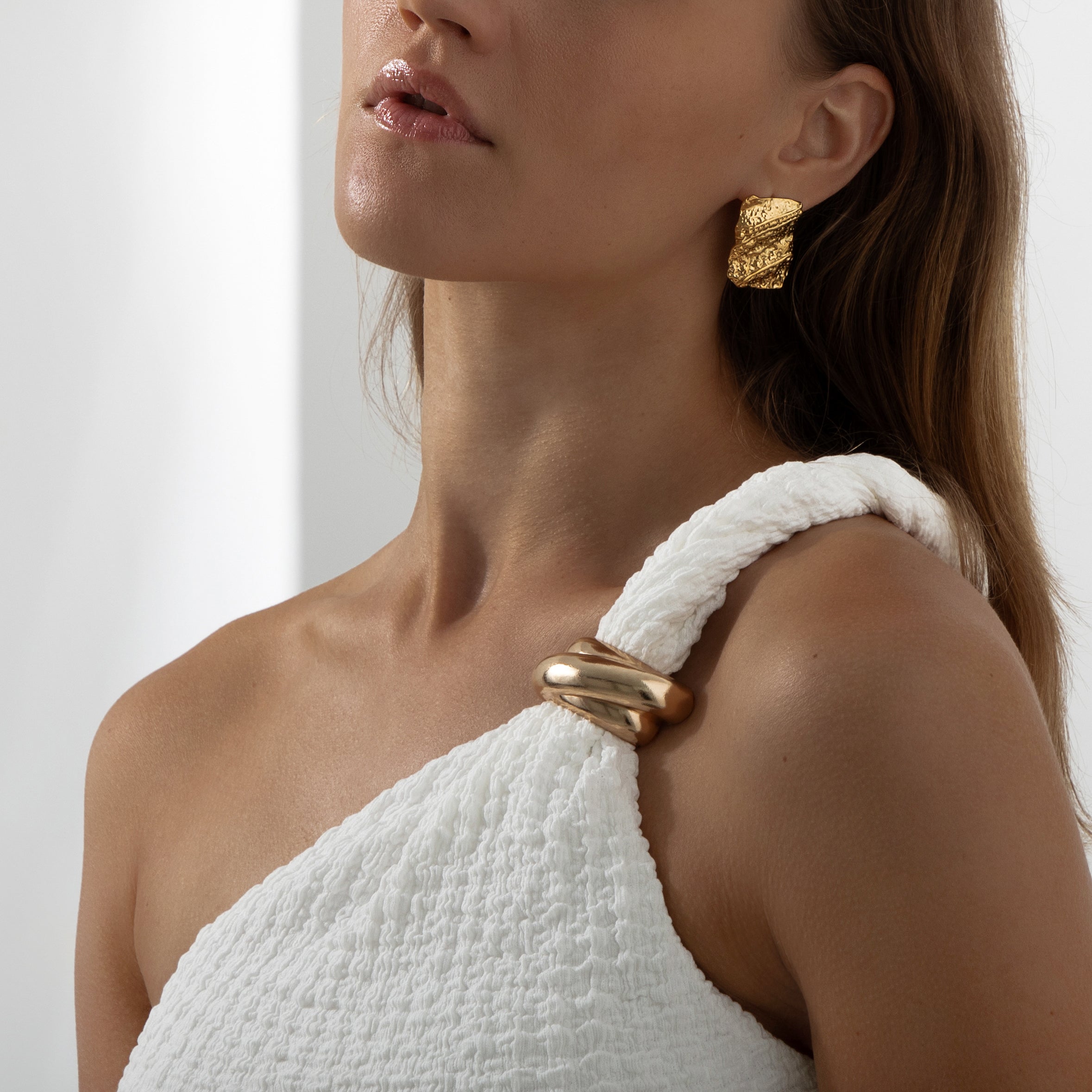 Model wearing gold Thalassa statement earrings with a sculptural molten finish and bold silhouette