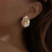 A pair of gold‑plated stud earrings, each shaped like three elegant, tapering wave arches that fan outward in a stylised, goddess-inspired design. The curved strands are smooth, mirror‑polished, and evenly spaced, creating a sense of movement and volume while remaining compact—approximately 1.3 cm tall from post to tip. They appear to sit snugly along the earlobe and fasten with standard push-back posts. The warm metallic sheen and sculptural silhouette evoke a graceful, contemporary luxury vibe.