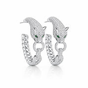A pair of silver hoop earrings featuring a detailed panther head design paved with clear stones, with small green emerald accents in the eyes, shown on a white background.