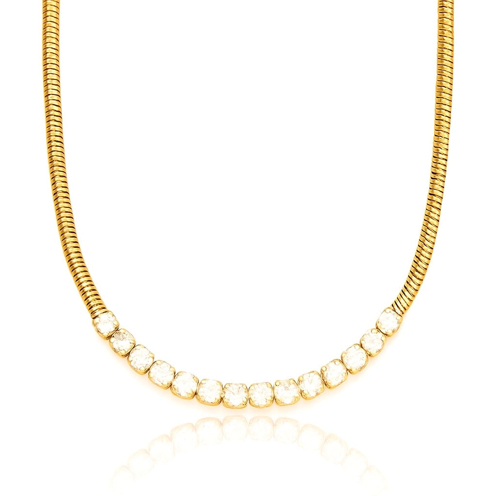 A layered-style necklace combining two distinct chains: one side is a classic slender snake chain, the other a sparkling row of cubic zirconia stones set in bezel-like settings (tennis chain). Both strands merge at a central point and rest together on the collarbone. The chains are 16K gold‑plated stainless steel, with the CZ strand approximately 4 mm wide. The necklace measures around 41‑46 cm, secured by a small lobster‑claw clasp with an extender. The warm gold finish contrasts the smooth metallic sheen 