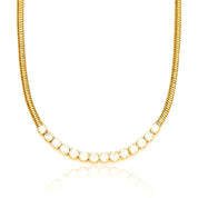 A layered-style necklace combining two distinct chains: one side is a classic slender snake chain, the other a sparkling row of cubic zirconia stones set in bezel-like settings (tennis chain). Both strands merge at a central point and rest together on the collarbone. The chains are 16K gold‑plated stainless steel, with the CZ strand approximately 4 mm wide. The necklace measures around 41‑46 cm, secured by a small lobster‑claw clasp with an extender. The warm gold finish contrasts the smooth metallic sheen 