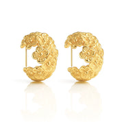 A pair of chunky, semi-circular hoop earrings photographed upright on a white background. Each hoop is crafted from stainless steel plated with glossy 18K gold, featuring an embossed design of small buttercup flowers densely covering the outer surface. The hoops are approximately 2.4 cm tall and 1.8 cm wide, with a smooth, reflective finish. They weigh around 15 g and appear waterproof and tarnish-resistant, making them an everyday-ready, statement floral accessory.