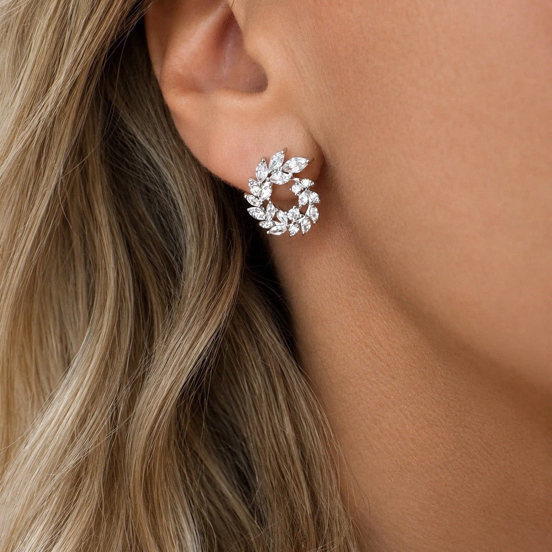 Model wearing a silver stud earring with a wreath design.