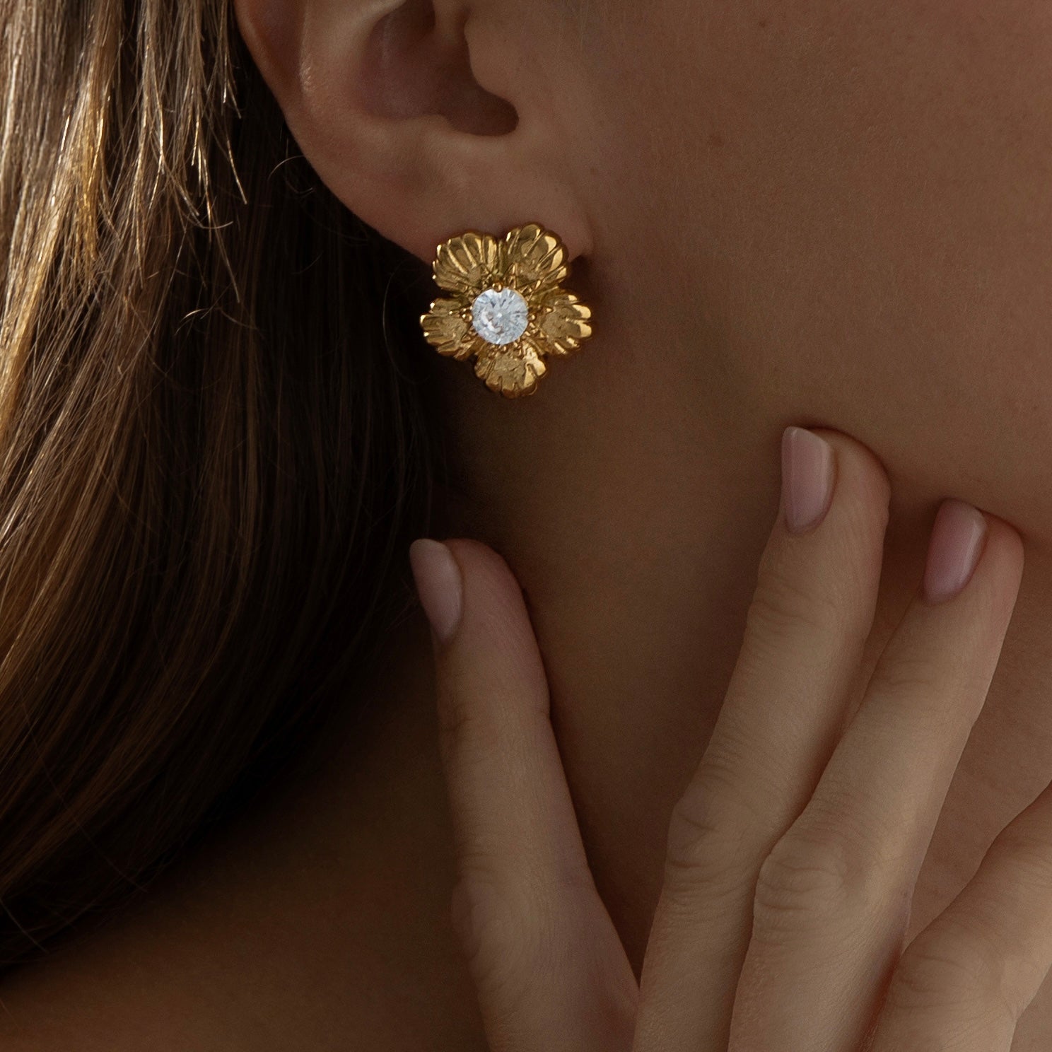 Bold tropical-inspired gold earrings featuring floral cut-out shapes in a semi-hoop design, accented with a sparkling crystal at the center. Made from lightweight, hypoallergenic, tarnish-resistant stainless steel — perfect for summer looks and all-day wear.