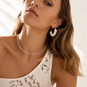 Model wearing a delicate pearl necklace and pearl hoop earrings. 