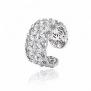 A silver-toned open cuff ring heavily set with clear marquise and round gemstones, shown on a white background with a soft reflection below.