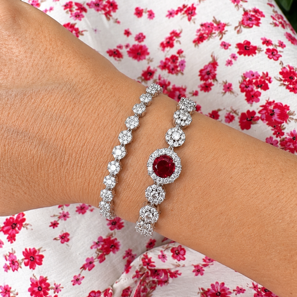 Silver bracelet with a red gemstone on a wrist against a floral background