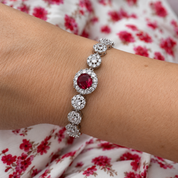 Silver bracelet with a red gemstone on a wrist against a floral background