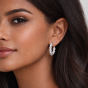Close-up of a woman wearing diamond hoop earrings with a neutral background