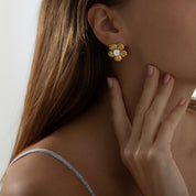 Bold tropical-inspired gold earrings featuring floral cut-out shapes in a semi-hoop design, accented with a sparkling crystal at the center. Made from lightweight, hypoallergenic, tarnish-resistant stainless steel — perfect for summer looks and all-day wear.