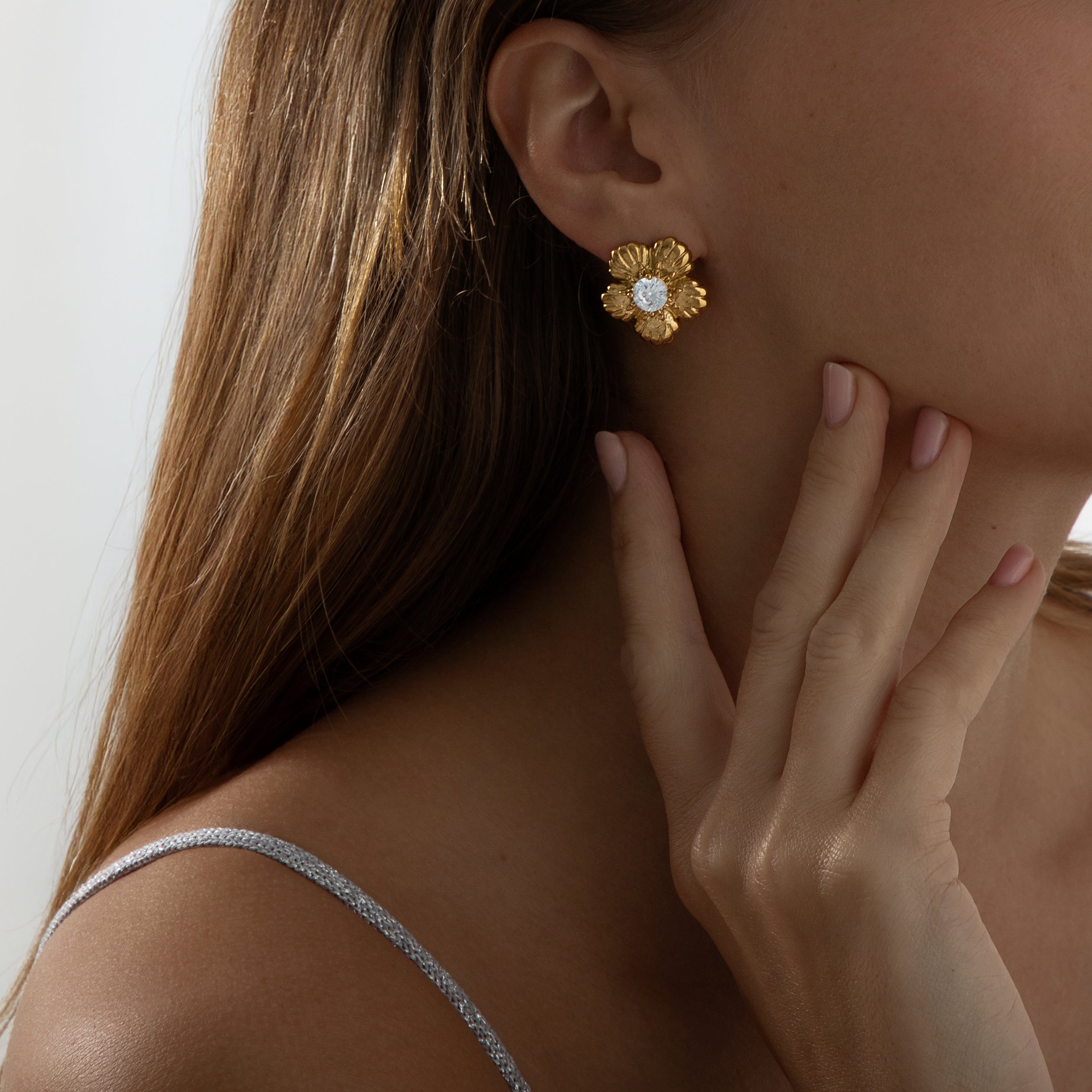Bold tropical-inspired gold earrings featuring floral cut-out shapes in a semi-hoop design, accented with a sparkling crystal at the center. Made from lightweight, hypoallergenic, tarnish-resistant stainless steel — perfect for summer looks and all-day wear.